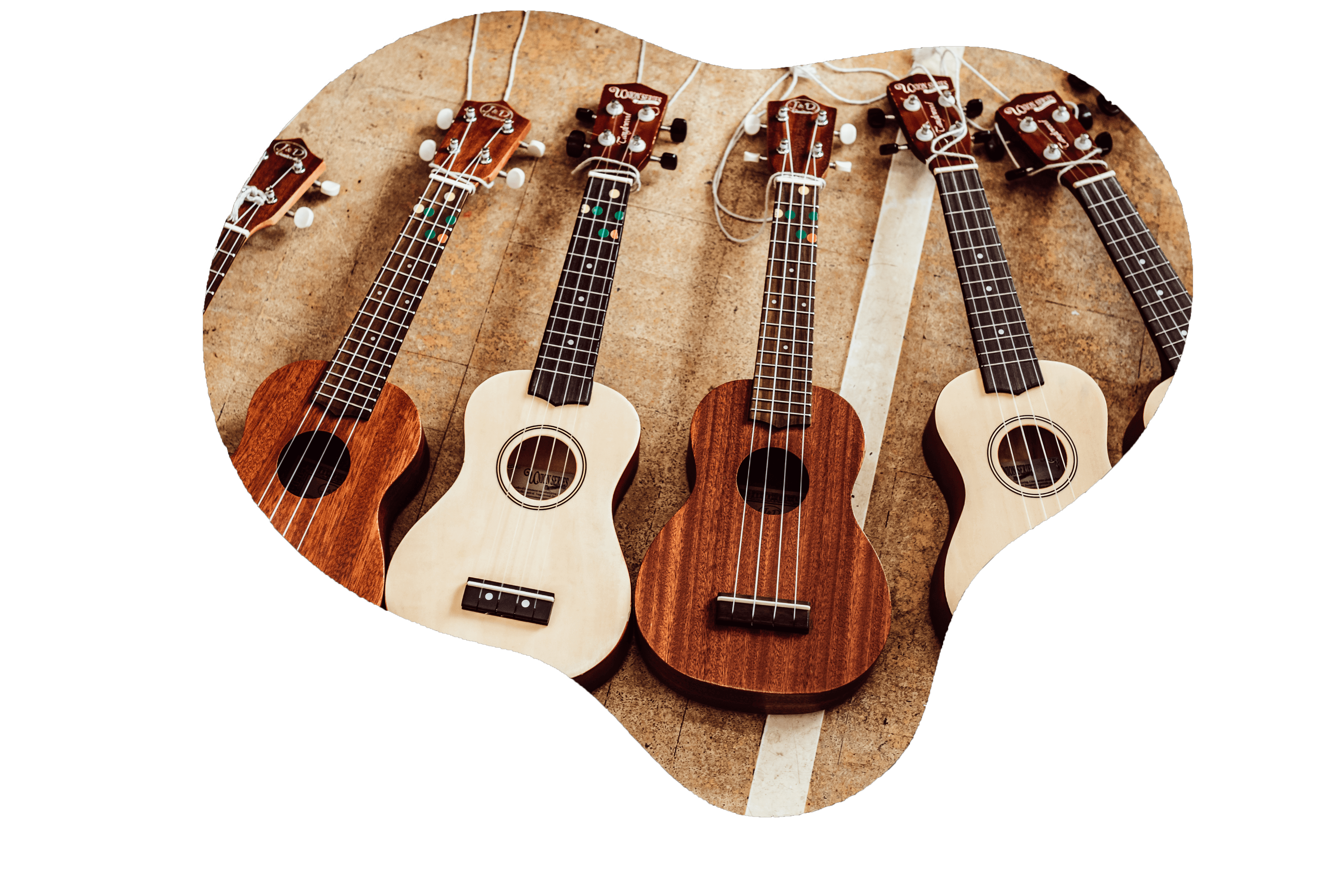 Four ukuleles with varying wood finishes are arranged in a fan shape on a surface with faded, broad stripes, suggesting a setting that is both creative and musical. The smallest ukulele at the front features a lighter wood and colorful fret markers, while the others display a more traditional look, hinting at an environment that values both learning and the joy of music.